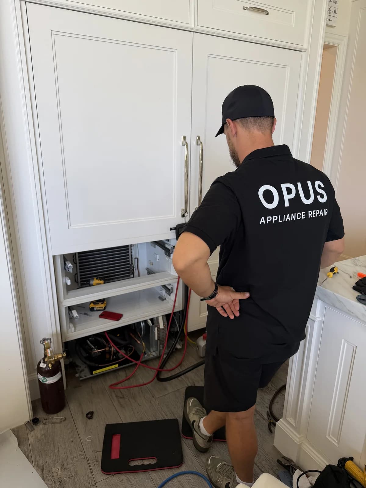 Andrew from OPUS performing compressor service on an undercounter refrigerator