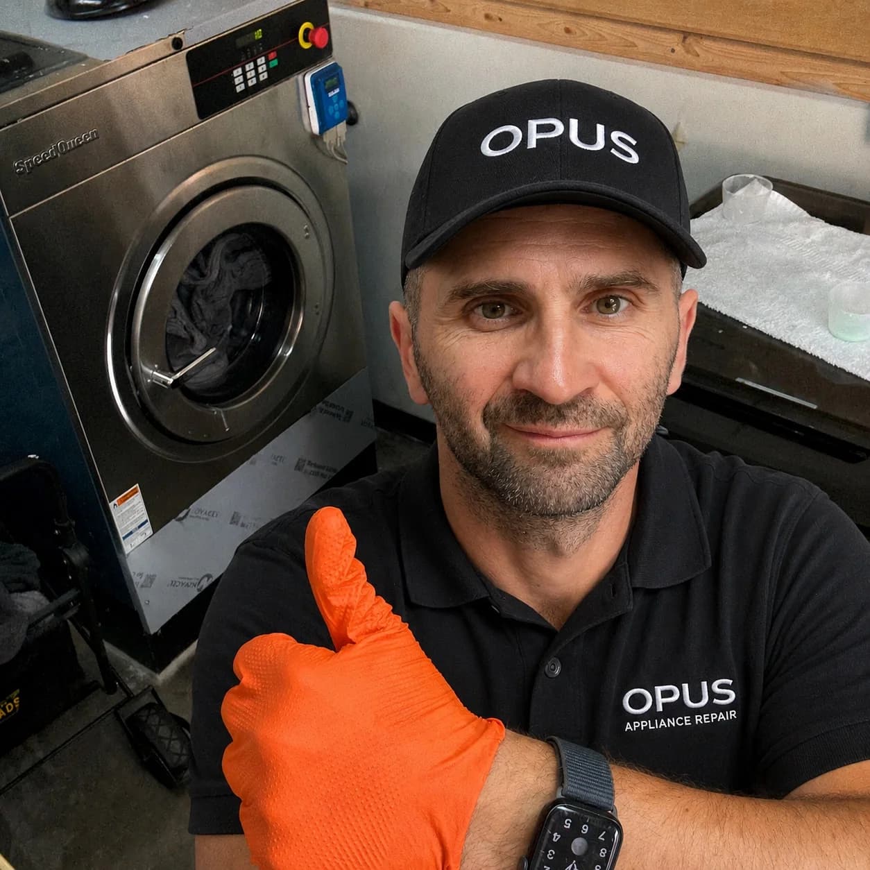 OPUS technician next to a Speed Queen commercial washer in a hotel laundry — drain pump replacement in San Diego